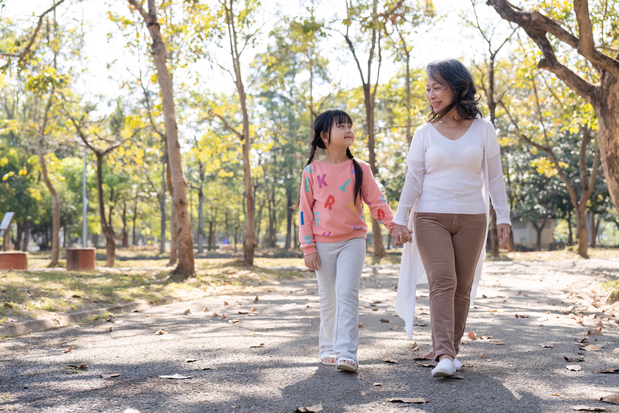 Happy grandmother and grandchild walking in public park