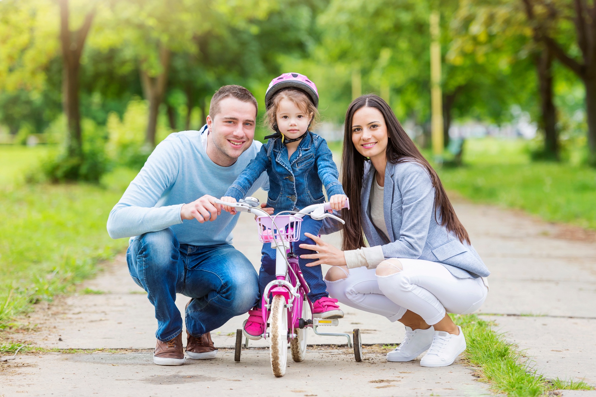 Smiling parents with daughter on bike